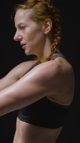 Foto-De-Estudio-De-Video-Vertical-De-Una-Mujer-Madura-Usando-Ropa-De-Gimnasio-Haciendo-Ejercicios-De-Estiramiento